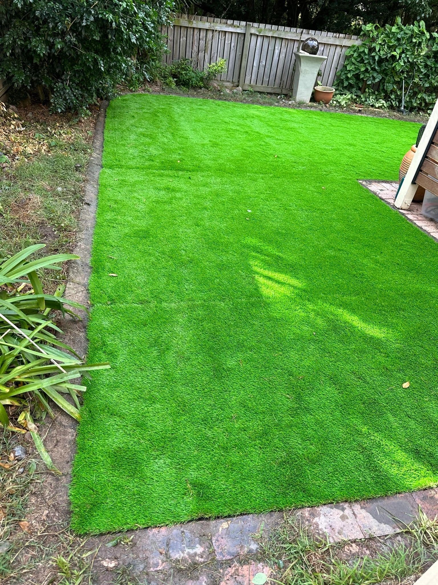 Small courtyard with bright artificial turf and garden edging