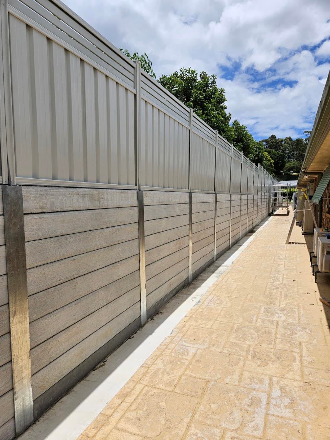Long grey Colorbond fence along a concrete side access path