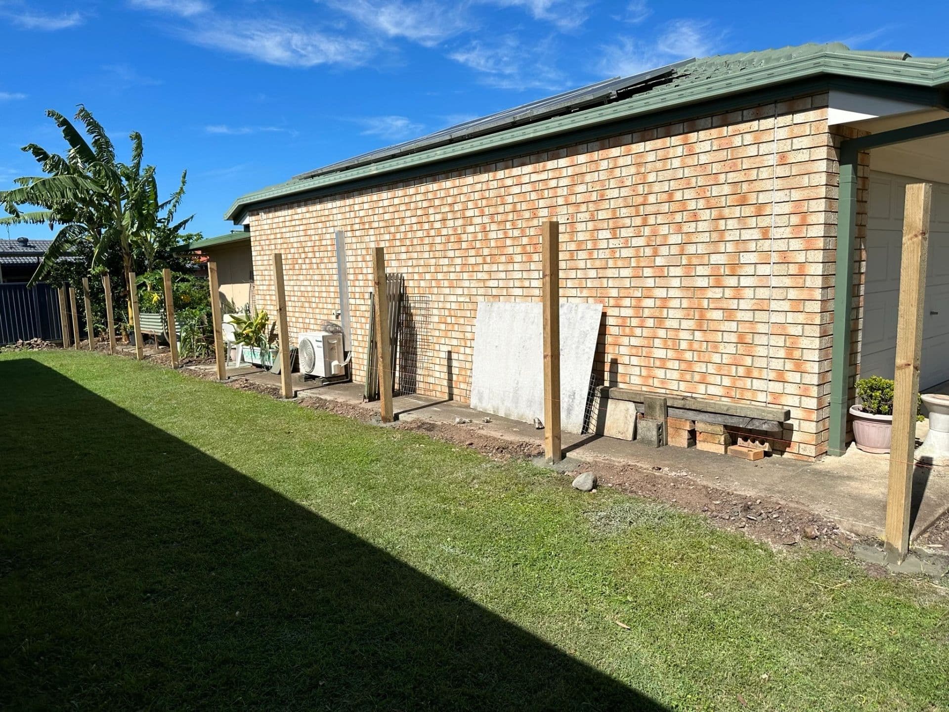Freshly laid natural turf in a backyard with a new timber fence and brick house