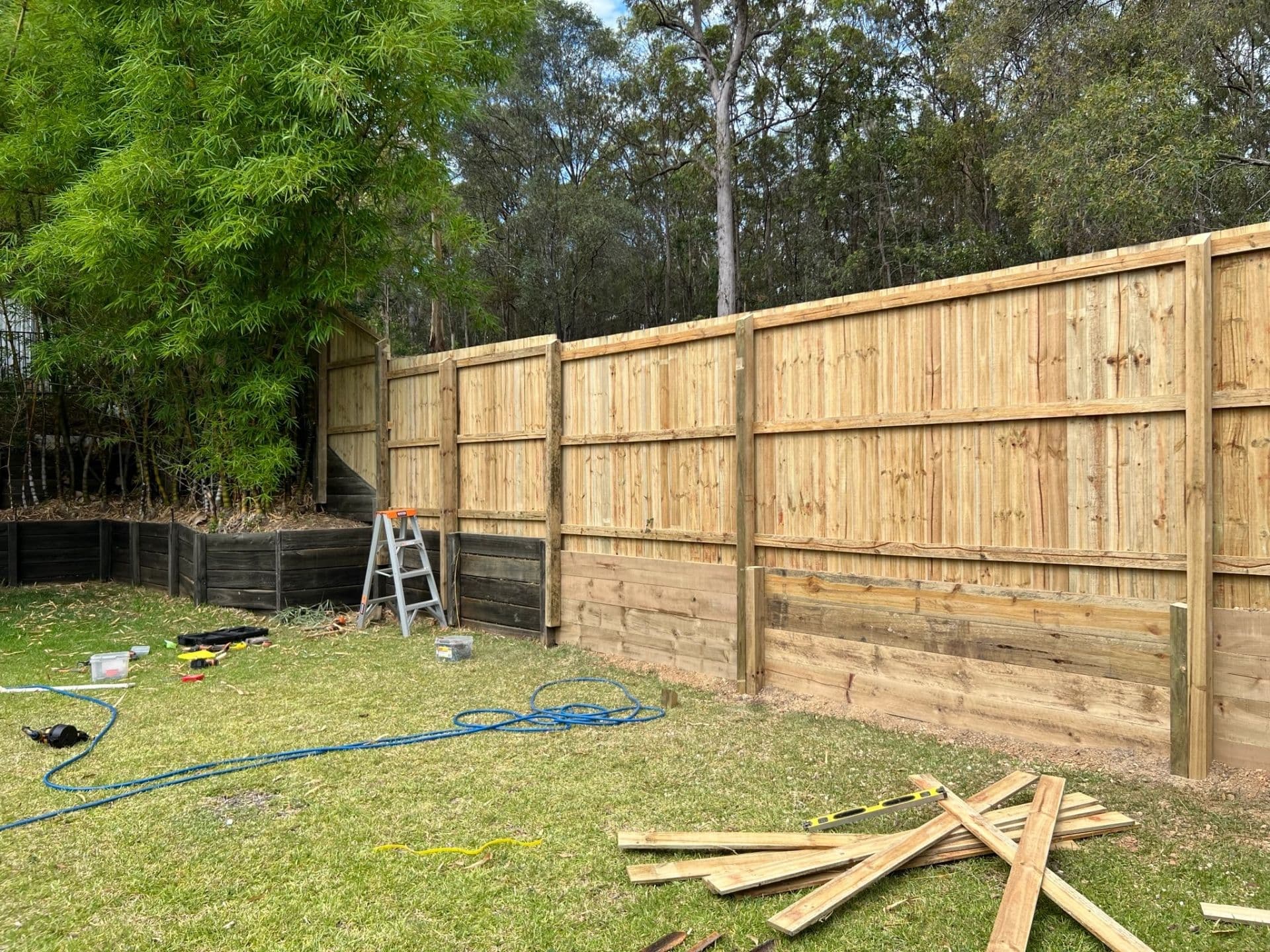 Tall timber fence going up along the back boundary of a lawn